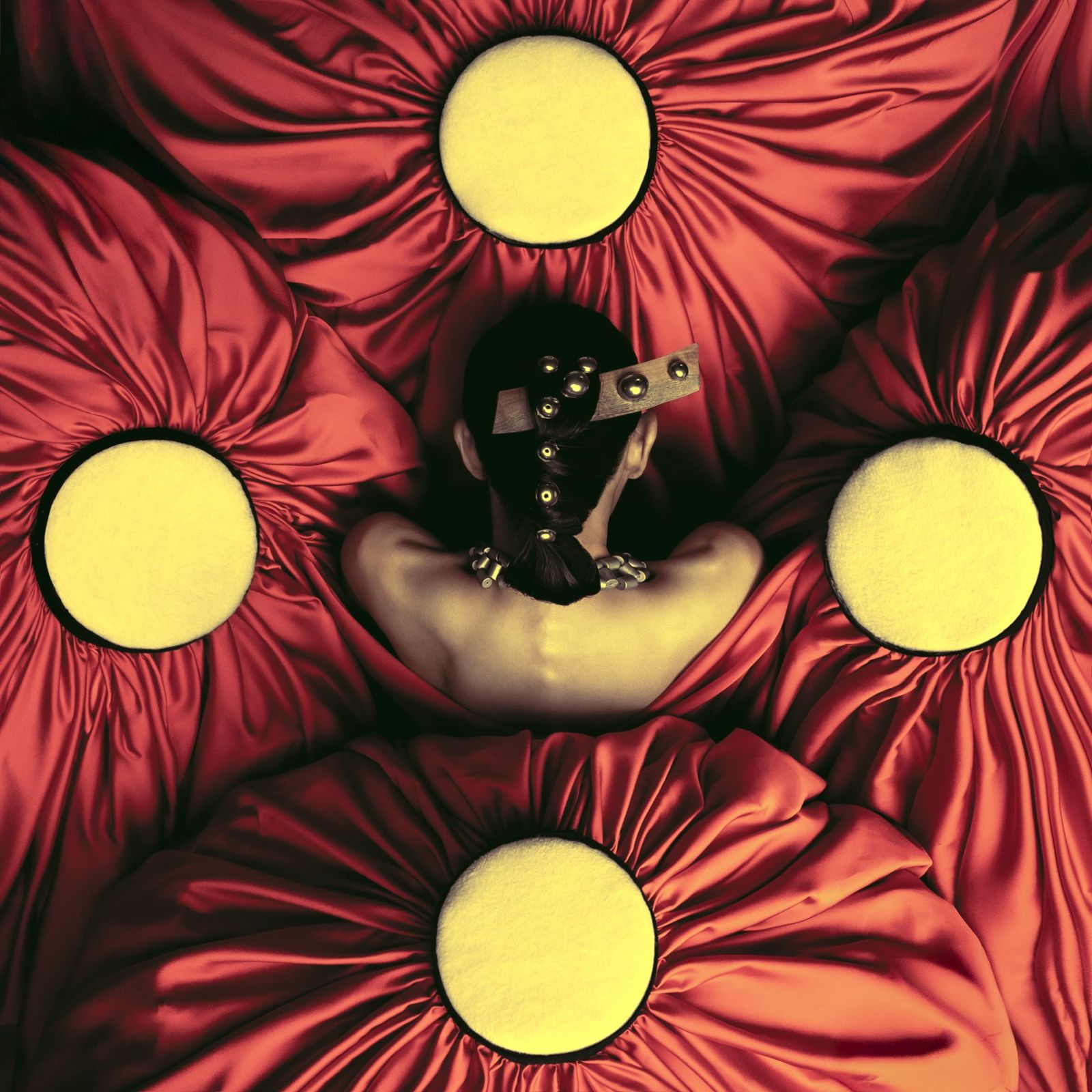 Red satin fanned out around a figure with four yellow discs