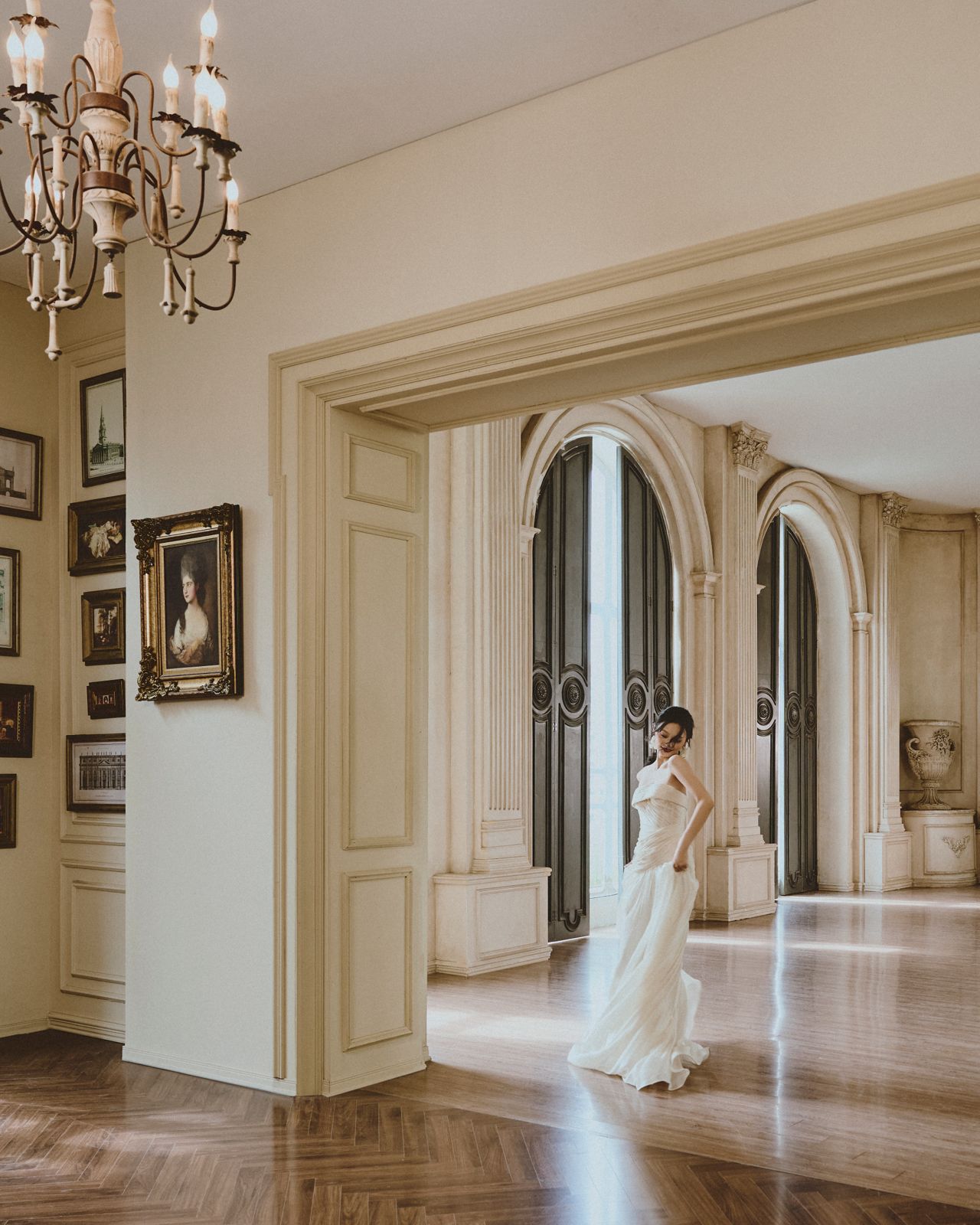 Ivory gown in an arched hall beneath a chandelier